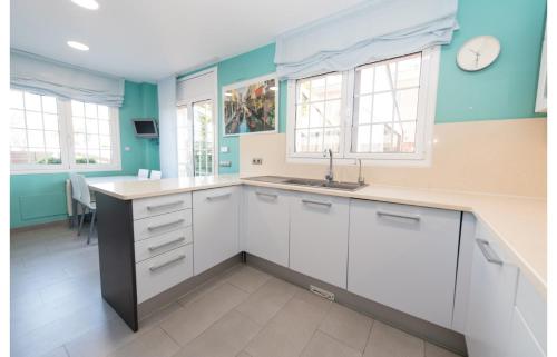 a kitchen with white cabinets and a sink and windows at HomeHolidaysRentals Royal in Pineda de Mar