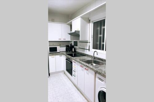 Una cocina blanca con gabinetes blancos y un fregadero. en Apartamento VISTA MAR, en Salou