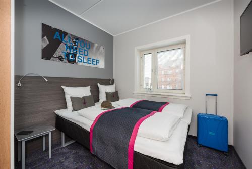1 dormitorio con 1 cama grande y 1 maleta azul en Cabinn Odense en Odense
