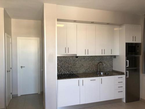 kuchnia z białymi szafkami i zlewem w obiekcie COSTA DAURADA APARTAMENTS - Stival Park 4 w mieście La Pineda