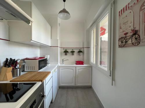 une cuisine avec des armoires blanches et une fenêtre dans l'établissement Studio Terrasse, à Cannes