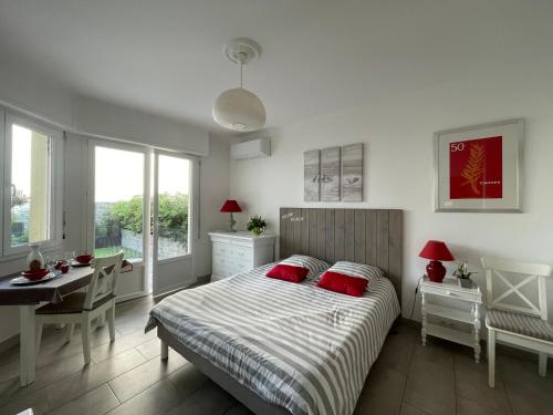 カンヌにあるStudio Terrasseのベッドルーム1室(赤い枕とテーブル付きのベッド1台付)