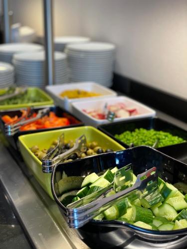 a buffet line with trays of vegetables on a counter at Arche Hotel Krakowska in Warsaw