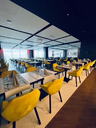 a dining room with tables and yellow chairs at Arche Hotel Krakowska in Warsaw