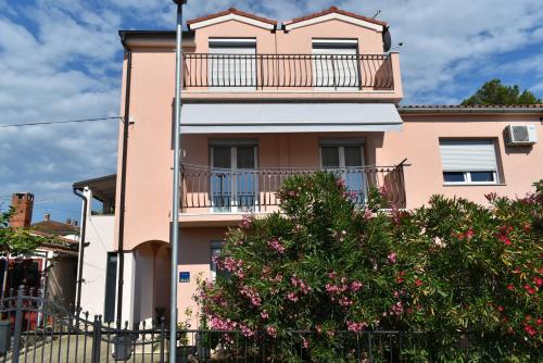 a pink house with a balcony and a tree at Studio Max in Rovinj