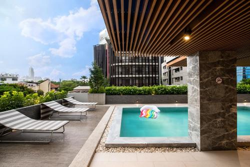 a pool with lounge chairs and an umbrella on a building at The Cotton Saladaeng Hotel in Bangkok