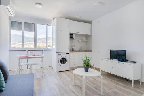 a kitchen with white cabinets and a table and a tv at Panoramic views cosy studio in Benalmádena