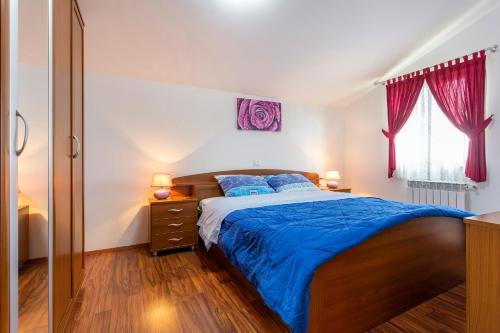 een slaapkamer met een bed met blauwe lakens en blauwe kussens bij Villa Mirela with a comfortable garden and pool in Grandići