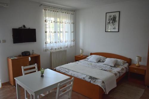 1 dormitorio con cama, mesa y TV en Studio Max with parking, en Rovinj