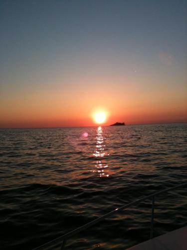 una puesta de sol en el océano con un barco en el agua en Casa Svalba, en Rovinj