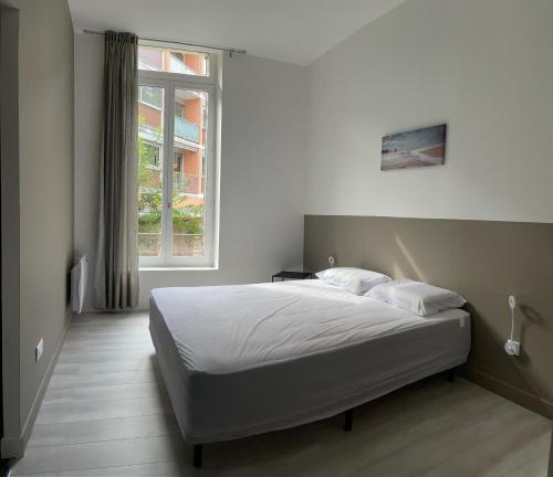 a bedroom with a white bed with a window at Bel Appartement 40 M2 sans linge de lit et de toilette in Vals-les-Bains