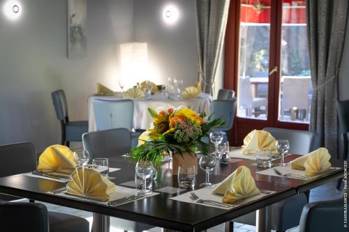 a dining table with a vase of flowers on it at Hôtel Restaurant Au Relais D'Alsace in Rouffach