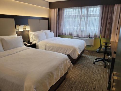 a hotel room with two beds and a window at Holiday Inn Express Maspeth by IHG in Queens