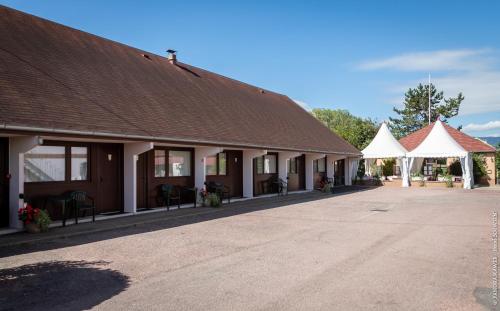 a building with a brown roof and white tents at Hôtel Restaurant Au Relais D'Alsace in Rouffach