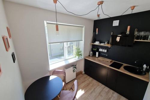 a kitchen with a table and a sink and a window at The sunny willow apartments in Liepāja