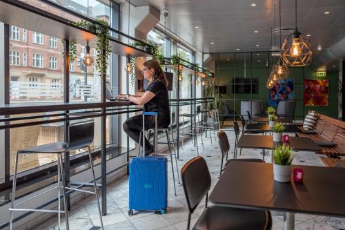 une femme avec une valise dans un restaurant avec des tables dans l'établissement Cabinn Odense, à Odense