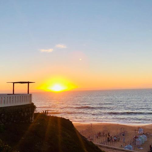 a sunset over the ocean with the sun setting on the beach at Apartamento T1 no centro TÊ-U in Torres Vedras
