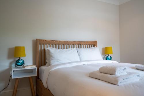 a bedroom with a large white bed with two lamps at Pleasant Putney home close to the tube station by UndertheDoormat in London