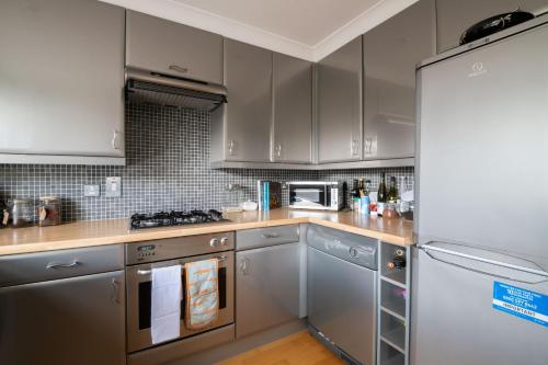 a kitchen with gray cabinets and a white refrigerator at Putney Perfection in London