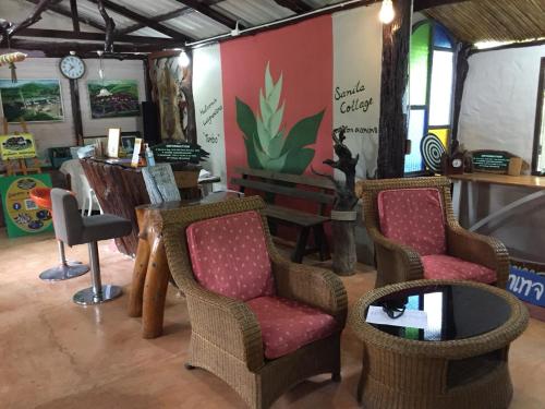 une chambre avec deux chaises, une table et une horloge dans l'établissement Sanita Cottage, à Chom Bung