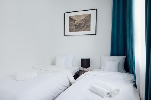 2 camas individuales en una habitación con cortinas azules en Stary Koszalin Hostel & Hotel Services, en Koszalin