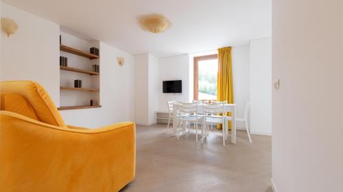 a living room with a table and a yellow chair at Italianway - Villa Tola in Valdisotto