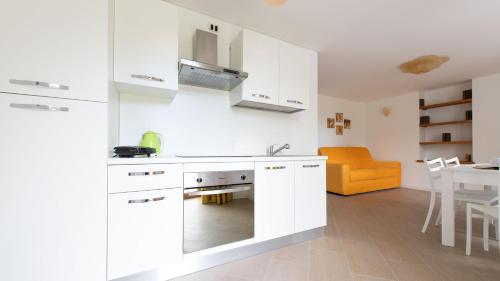 a kitchen with white cabinets and an orange couch at Italianway - Villa Tola in Valdisotto