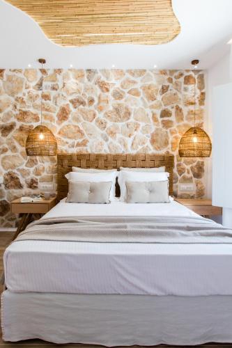 a bedroom with a large bed with a stone wall at Arsenis Luxury Villas in Plaka