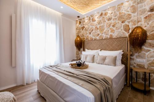 a bedroom with a large bed with a stone wall at Arsenis Luxury Villas in Plaka
