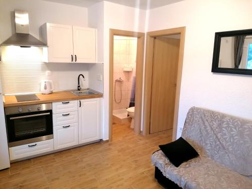 a kitchen with white cabinets and a couch in a room at Apartments Amfora in Gdinj