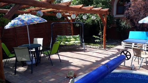 a pool with a table and chairs and an umbrella at Katica Vendégház Somogyvár - Ladybird Villa Somogyvár in Somogyvár