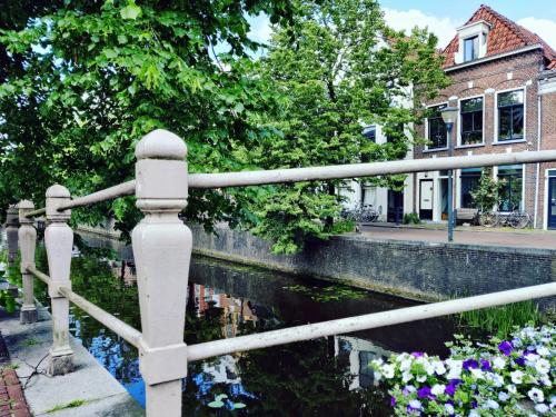 a fence next to a canal with flowers at Bed in de binnenstad ♡ bed downtown in Leeuwarden