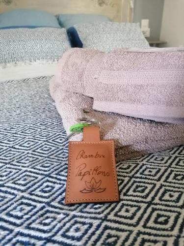 a tag sitting on top of a bed with towels at Les Mesanges in Combrand