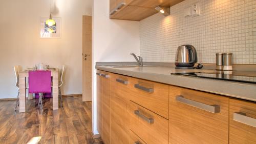 a kitchen with a sink and a table with a purple chair at Boromeum Residence in Hradec Králové