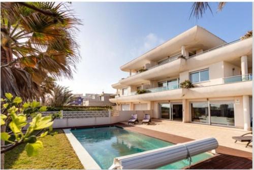una casa grande con piscina frente a ella en VILLA BLANCA, La MANGA, POOL& SEA San Javier, Murcia en La Manga del Mar Menor