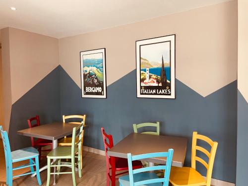 a dining room with two tables and colorful chairs at Ostello Del Porto in Lovere