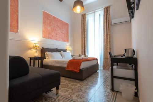 una camera con letto, sedia e divano di Liberty Palace a Palermo