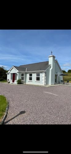 a white house with a large driveway in front of it at Rose Cottage in Killarney