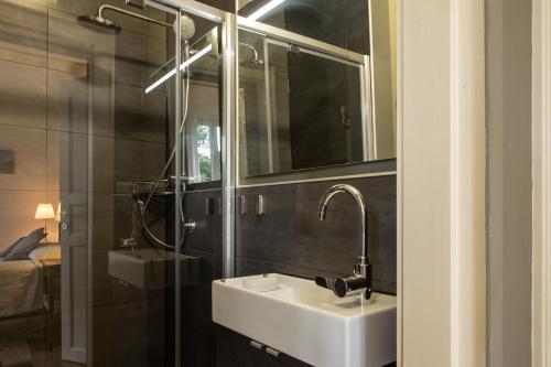 a bathroom with a sink and a mirror and a shower at B&B Villa le Ortensie in Faggeto Lario 
