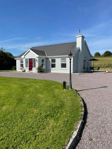 a white house with a pole in the grass at Rose Cottage in Killarney
