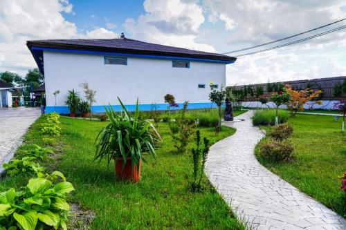 a garden with a white building and a path at Hotel Sunrise in Crisan