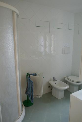 a white bathroom with a toilet and a sink at Historic Center Apartment with Private Garage in Montalcino