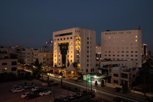 a city at night with cars parked in a parking lot at Bristol Hotel in Amman
