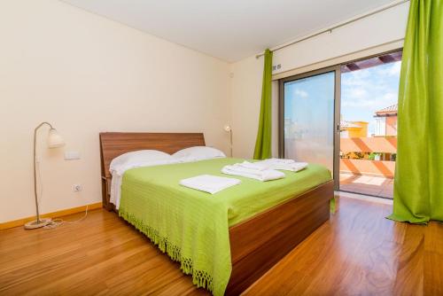 1 dormitorio con cama verde y ventana grande en Orange Lux Villa, en Luz de Tavira