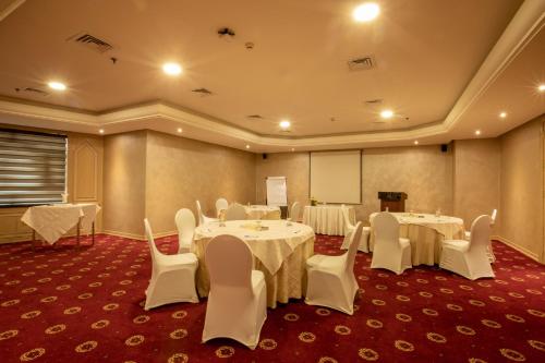a conference room with white tables and white chairs at Bristol Hotel in Amman