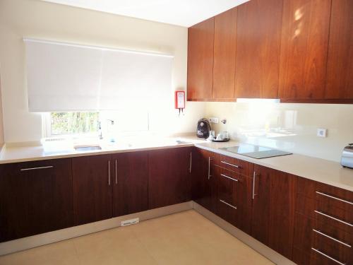 a kitchen with wooden cabinets and a window at Anis Lux Tavira Residence Villa 5M in Luz de Tavira