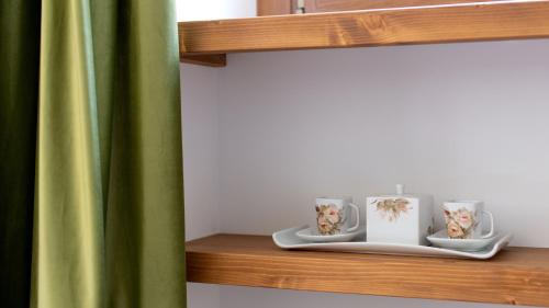 a shelf with three cups and a green curtain at Italianway - Villa Tola in Valdisotto