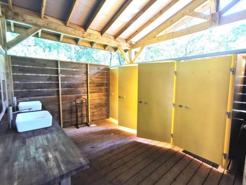 a large room with yellow doors and a wooden floor at Le Tipi Tropical au bord de la rivière in Mios
