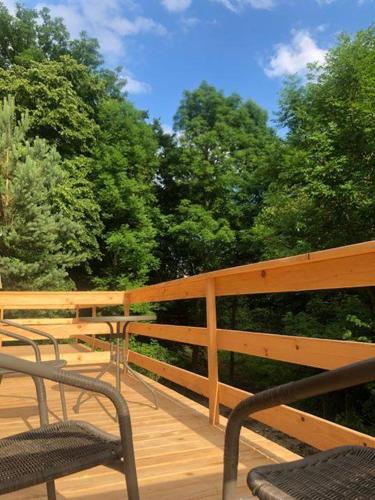 a wooden deck with two chairs and trees at Apartamenty Domek na Roztoczu in Horyniec Zdrój