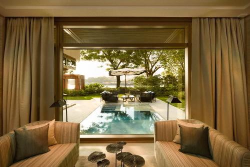 a living room with a large window and a swimming pool at Capella Bangkok in Bangkok